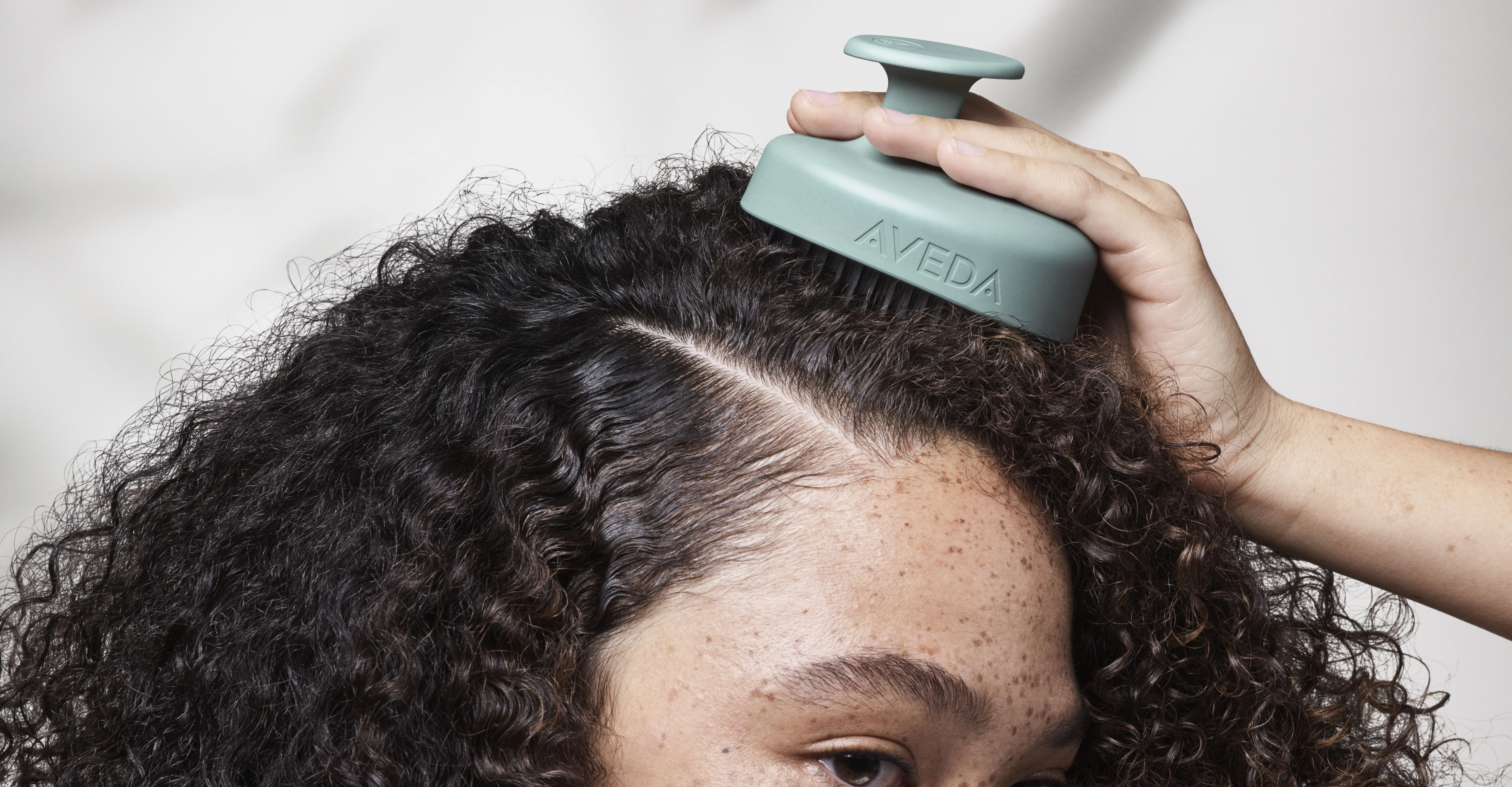 Frau wendet Aveda Scalp Solutions Stimulating Scalp Massager und Treatment an