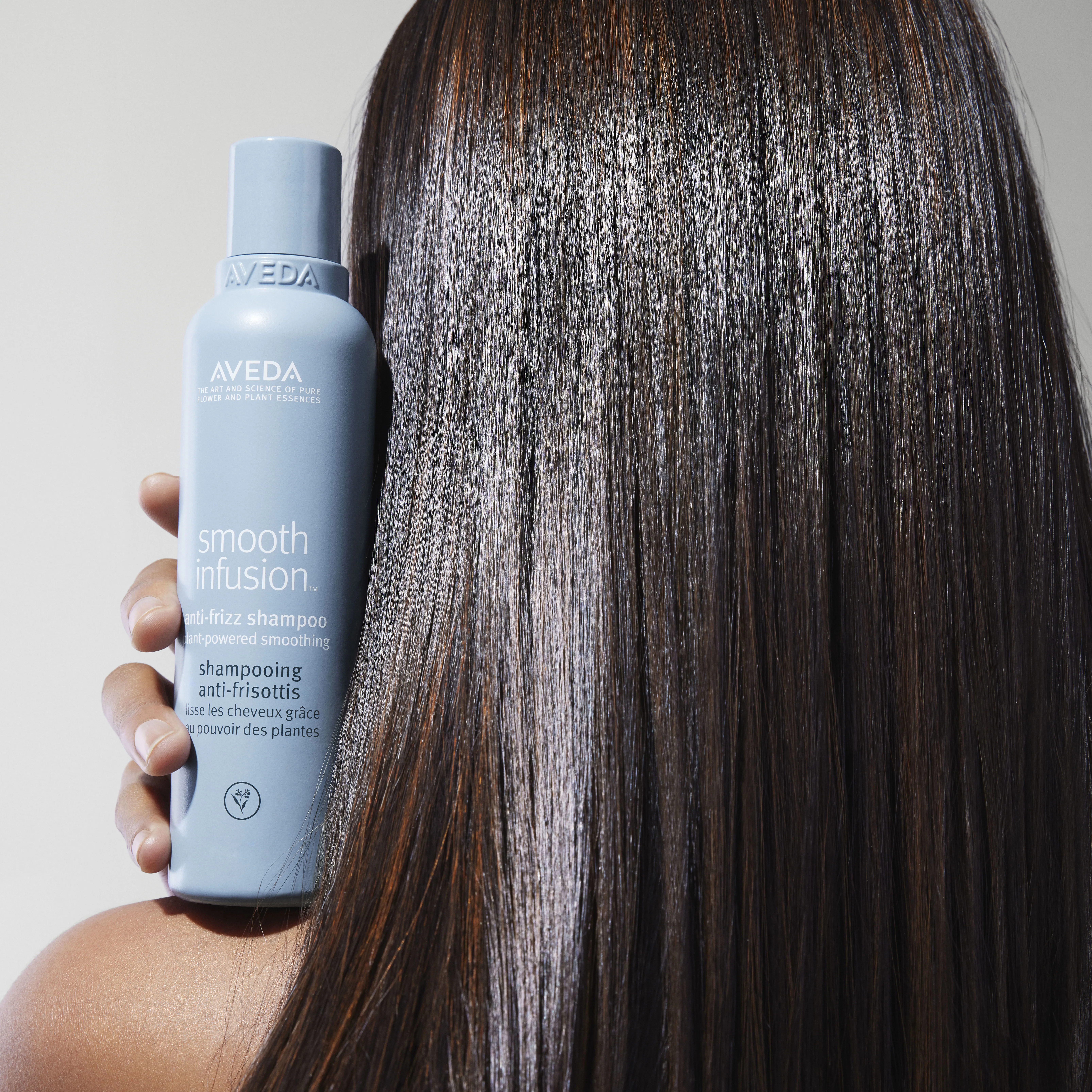 Model mit Aveda Smooth Fusion Shampoo in der Hand