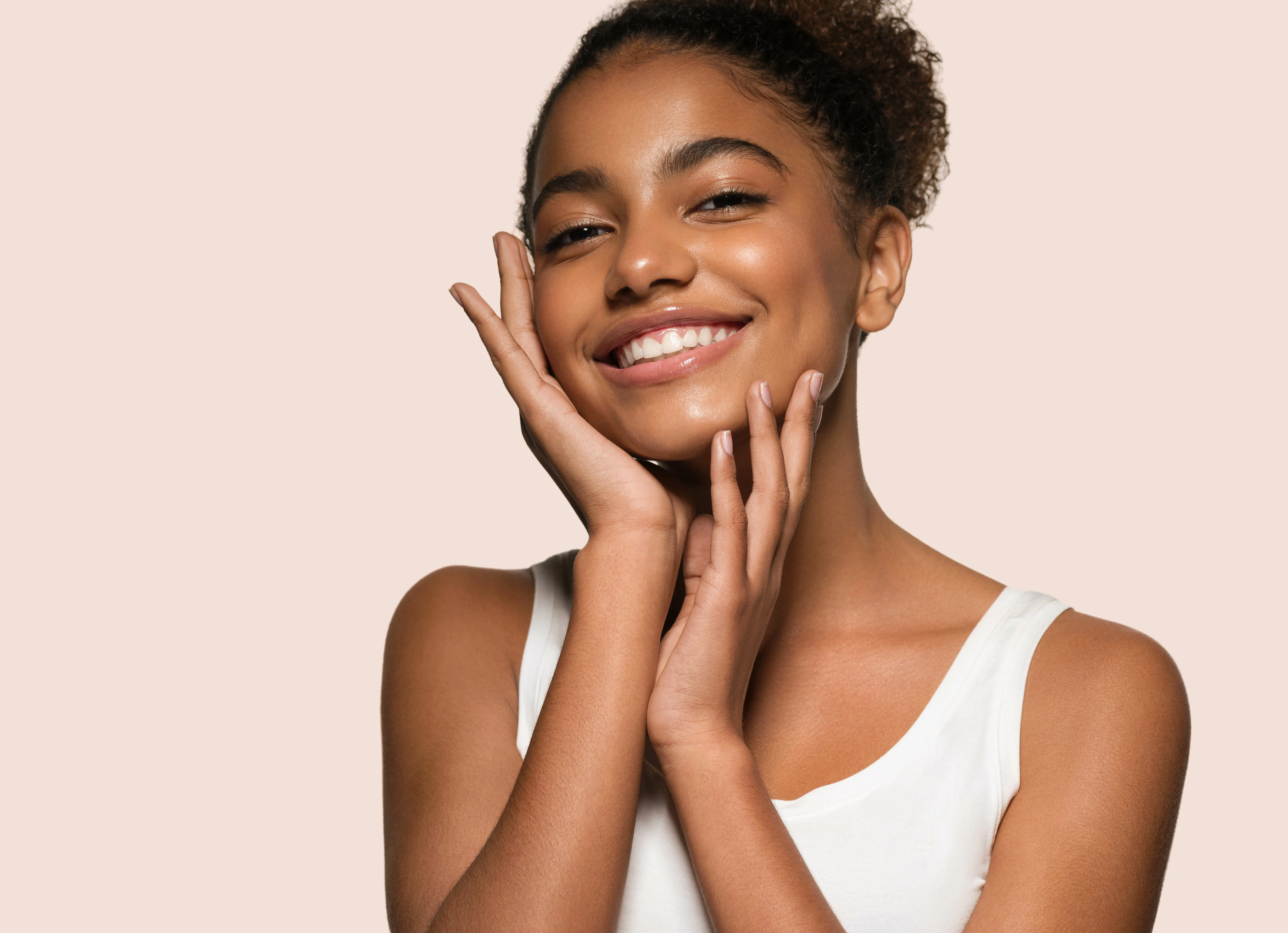 Frau mit makelloser Haut fasst sich ins Gesicht